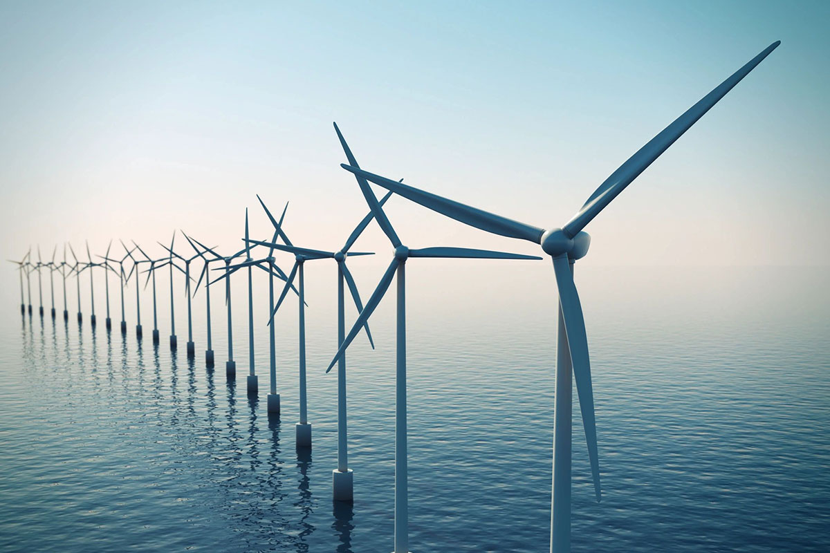 A row of wind turbines in the middle of water.